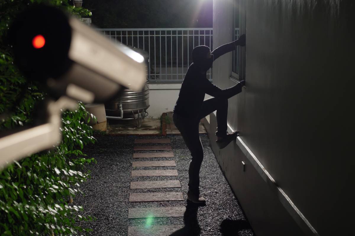 Night vision security camera capturing burglar entering home at night