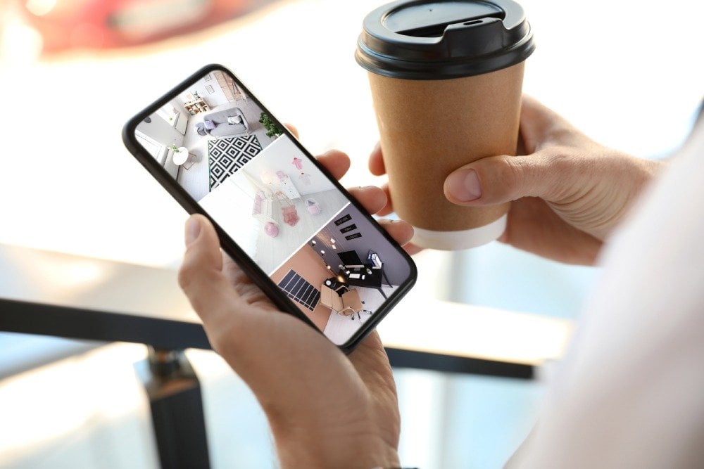 Person monitoring home security footage on a phone screen.