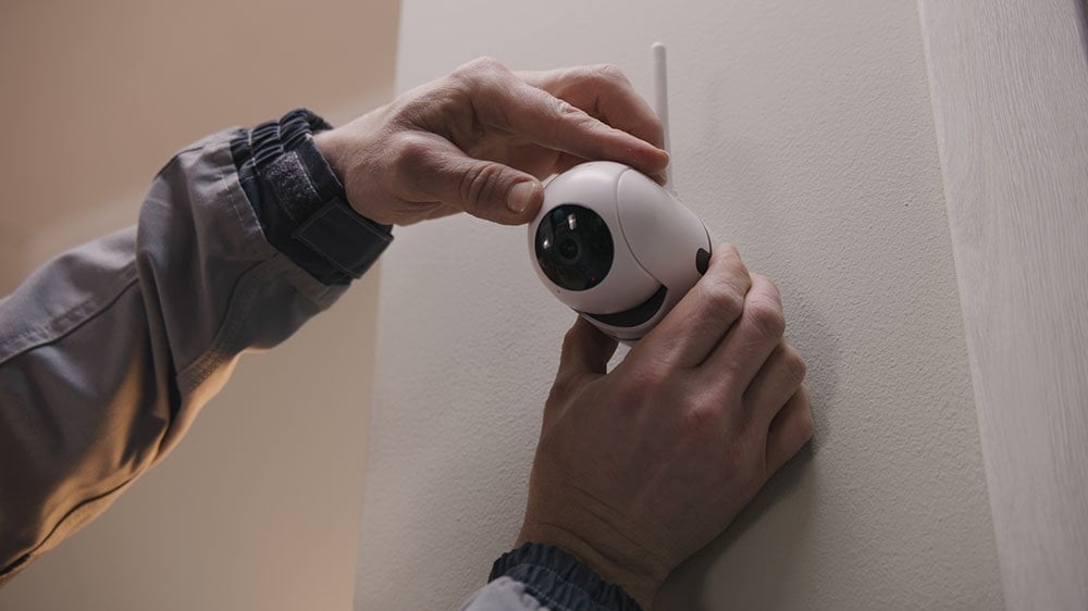 A man setting up a camera on his interior wall