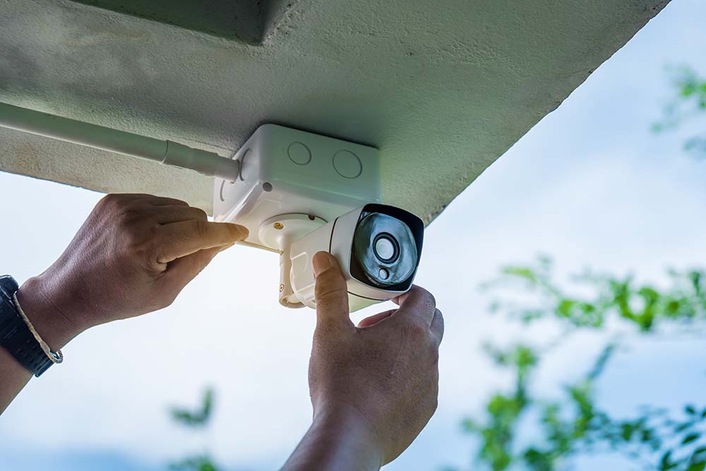 A technician installing a camera under the eaves.