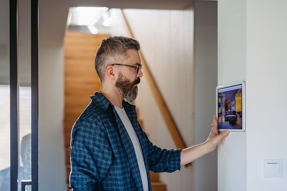 A man looking at a security system on a wall.